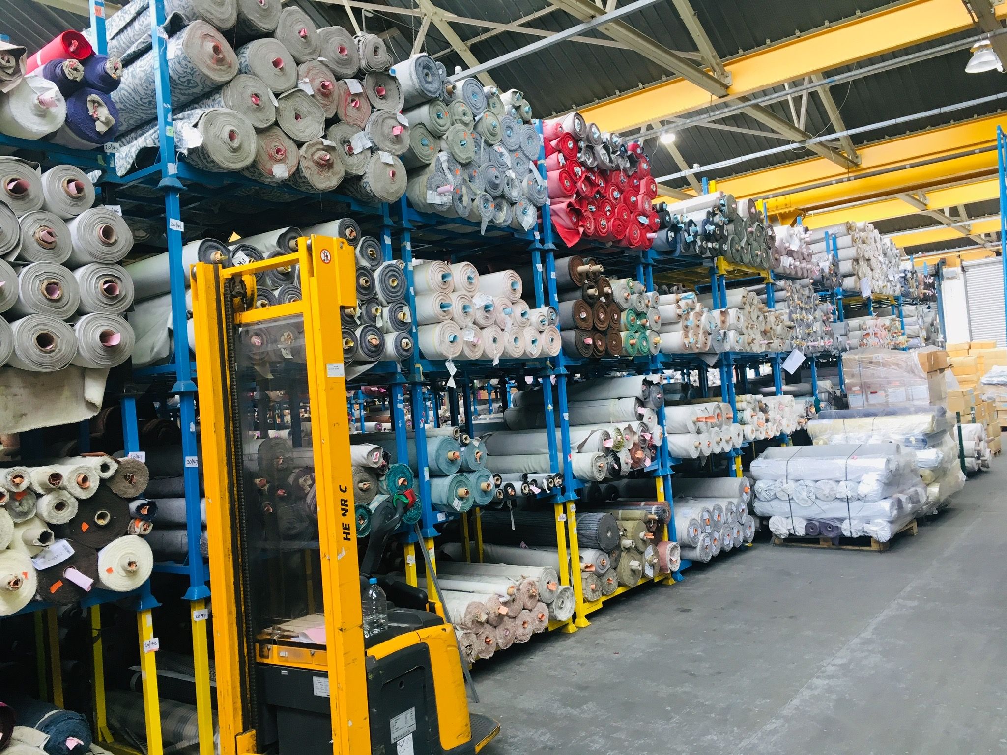 Rolls of fabric stacked on tall racks in the M&S furniture factory warehouse